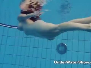 Redheaded enchantress swimming nude in the pool