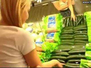 Młody płeć żeńska pieprzy ogórek w publiczne supermarket